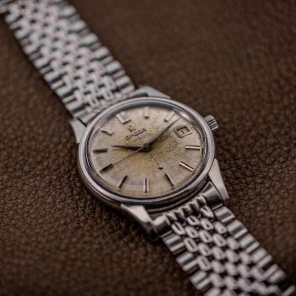 Omega Constellation 14393 under a scratched crystal, darkened dauphine hands above applied baton hour markers