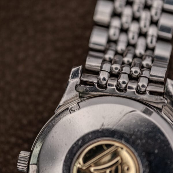 Omega 14393 case corner, crown profile and steel bracelet end link showing decades of honest wear