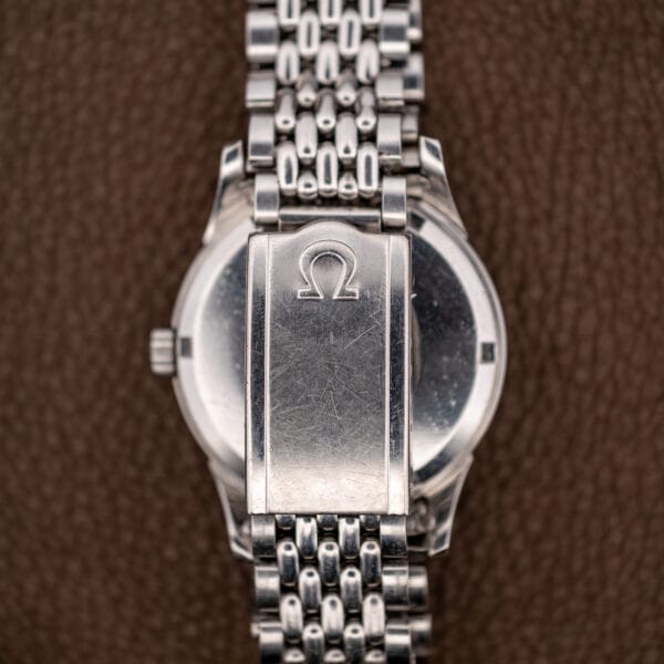 Omega folding clasp marked with the Omega symbol, resting over the scratched steel caseback of the 14393