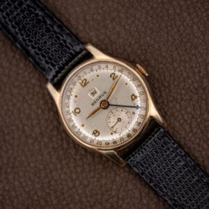 Vintage Benrus pointer date and day wristwatch, white Arabic numeral dial, black leather strap, angled front view
