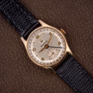Vintage Benrus pointer date and day wristwatch, white Arabic numeral dial, black leather strap, angled front view