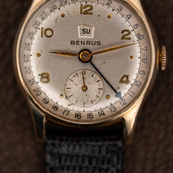 Macro of the Benrus CE-13 white dial showing age spotting, blued pointer date hand and day aperture
