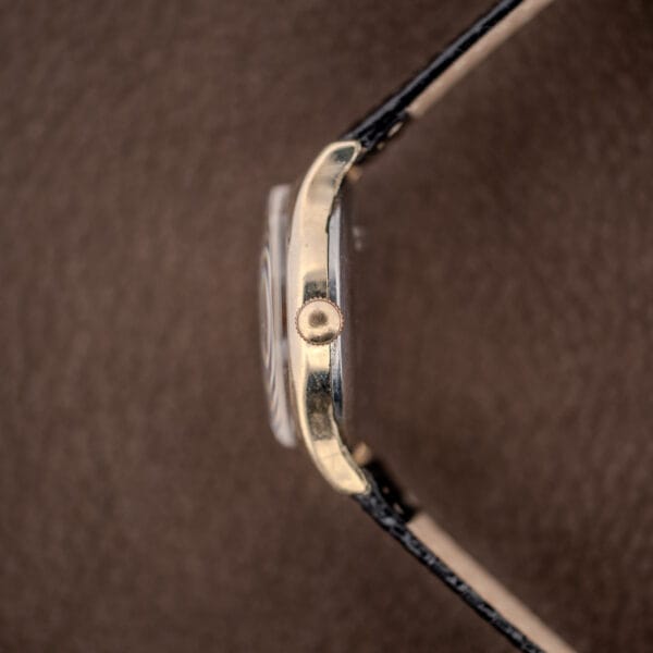 Side profile of the Benrus CE-13 case with unsigned knurled crown and worn gold-tone case flank