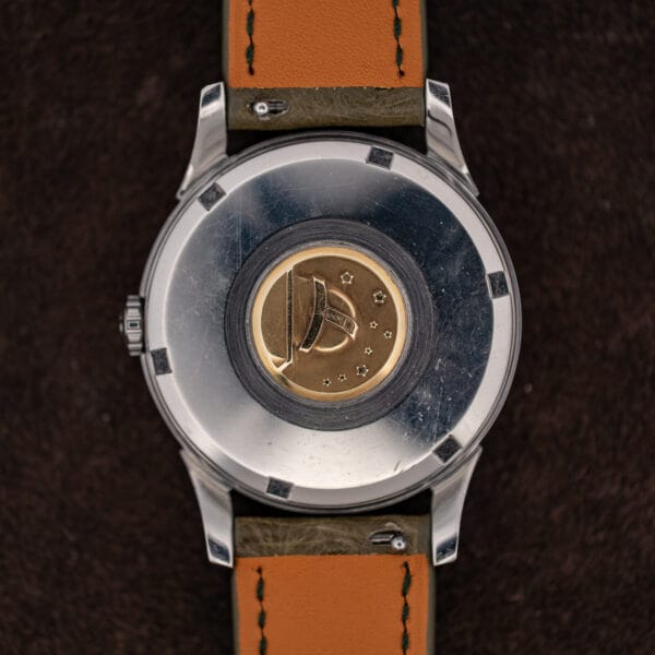Omega Constellation caseback with worn gold observatory medallion and scratched stainless steel surround