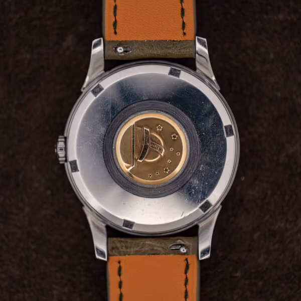 Omega Constellation caseback with worn gold observatory medallion and scratched stainless steel surround