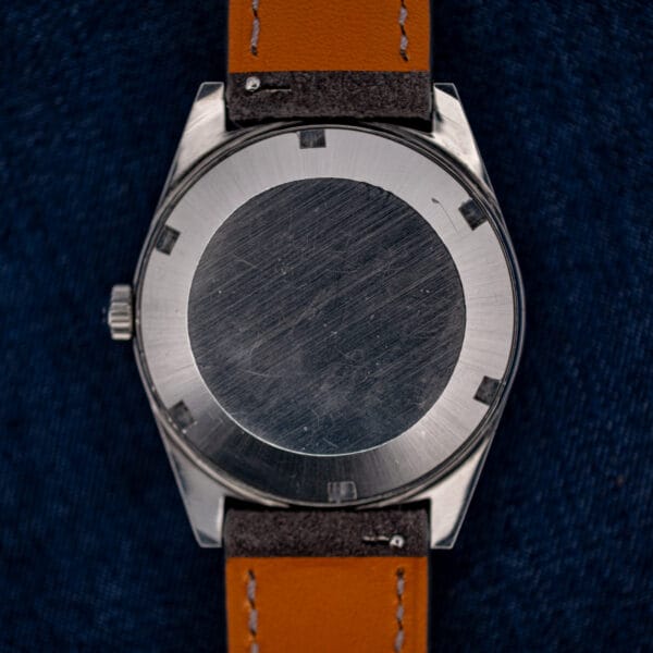 Omega 166.041 stainless steel caseback exterior showing honest scratches and wear across the brushed outer ring