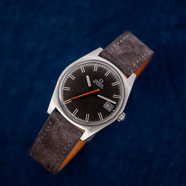 Omega Geneve 166.041 with beige lume plots along the minute track and bright orange central seconds