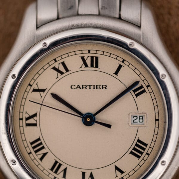 Cartier Cougar dial macro showing black Roman numerals, railroad minute track and blued hands on eggshell