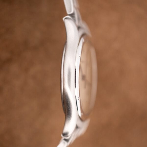 Cartier Cougar 987904 slim case flank, brushed steel sides meeting the polished bezel edge and crystal