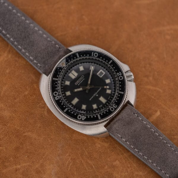 Seiko Captain Willard 6105-8119 on anthracite suede, showing case scratches and softened cushion case edges