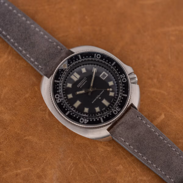 Seiko Captain Willard 6105-8119 on anthracite suede, showing case scratches and softened cushion case edges