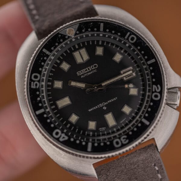 Macro of the Seiko 6105 dial upper half, SEIKO AUTOMATIC printing and evenly aged cream lume markers
