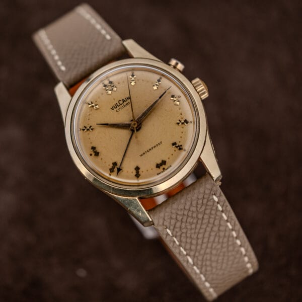 Vulcain Cricket gold capped case showing wear through at the lower right lug, beside a patinated dial