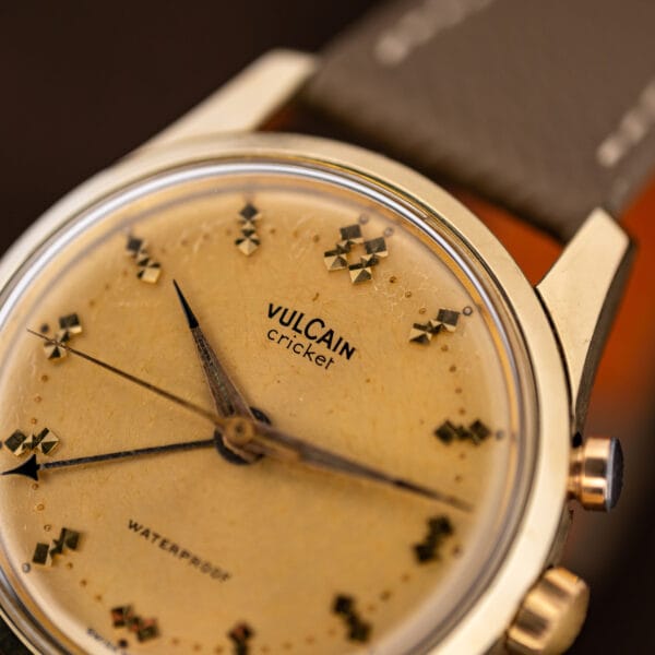 Macro of the Vulcain Cricket dial upper half, crackled surface, faceted markers, case profile at right