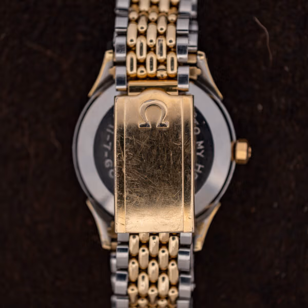 Gold tone Omega signed clasp on two-tone expansion bracelet, scratched from decades of wear