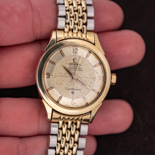 Omega Constellation 2852-9 SC held in hand, prominent diagonal scratch visible across acrylic crystal