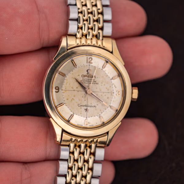 Omega Constellation 2852-9 SC held in hand, prominent diagonal scratch visible across acrylic crystal