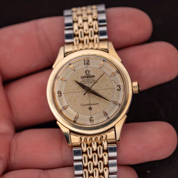 Vintage Omega Constellation pie-pan dial watch in hand, heavy speckled patina and two-tone bracelet