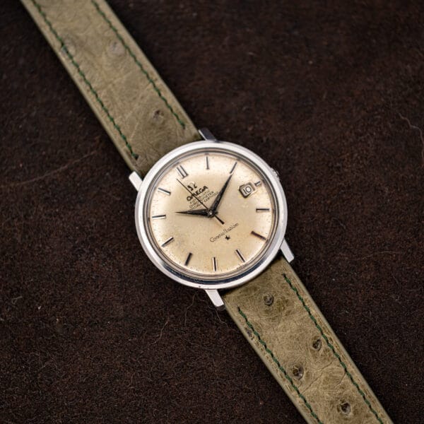 Full view of Omega Constellation 168.004 with olive ostrich strap extended diagonally across brown cloth