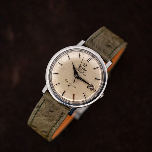 Omega Constellation 168.004 standing at an angle with its olive ostrich strap curved behind the case