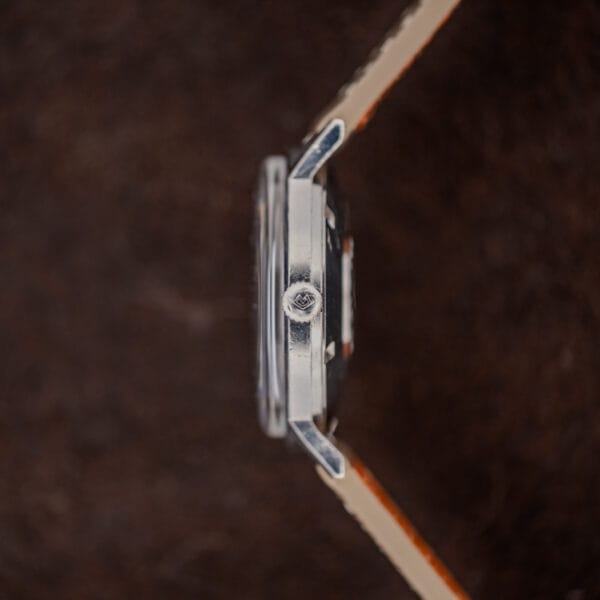 Crown-side profile of Movado Kingmatic 15161 showing the signed winding crown, raised crystal and angled lugs