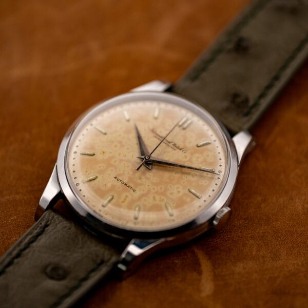 Angled IWC front view showing the mottled dial, winding crown and olive ostrich strap