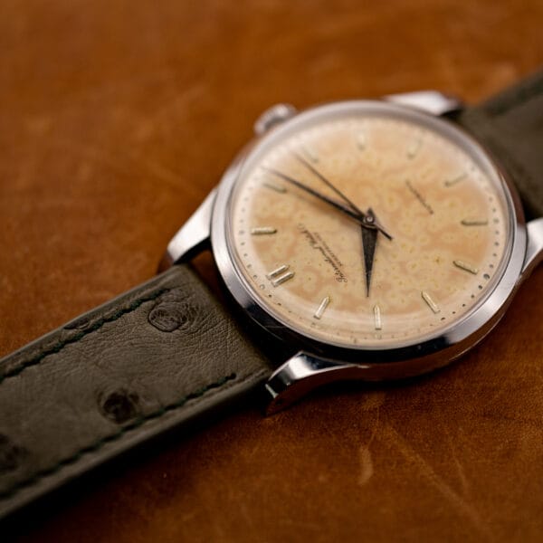 Low oblique view of the IWC showing its smooth bezel, raised crystal and textured ostrich strap