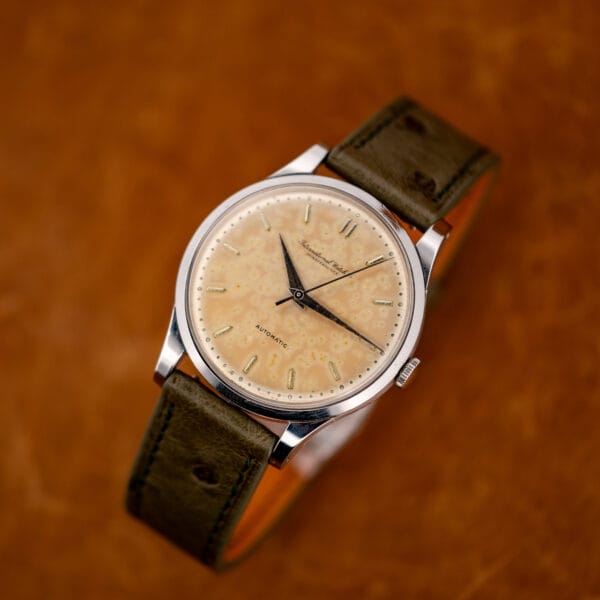 IWC automatic posed diagonally with the olive ostrich strap curved behind its stainless steel case
