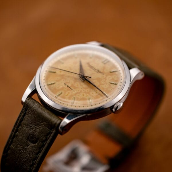 Low-angle IWC view with the winding crown and lower lugs above the curved olive ostrich strap