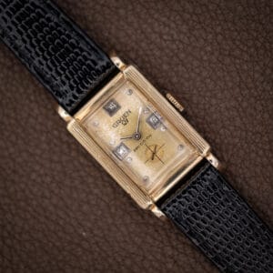 Gruen Precision 335/756 rectangular tank with champagne dial and black lizard strap on a brown surface