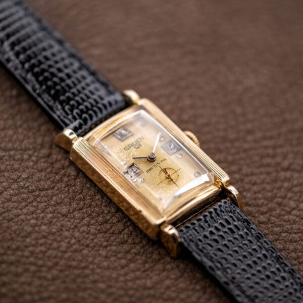 Angled Gruen Precision 335/756 with the lower lugs, champagne dial and textured black strap in view