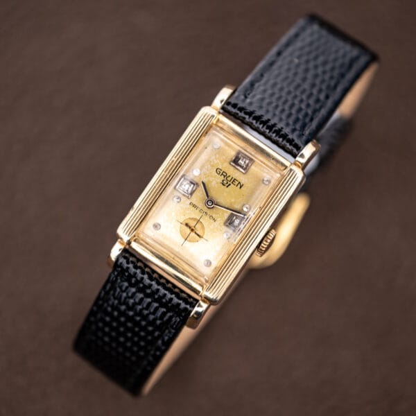 Gruen Precision 335/756 displayed with its black lizard strap curved behind the rectangular case and champagne dial