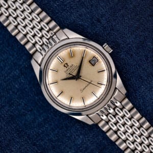 Omega Seamaster 168.024 chronometer with date display and beads-of-rice bracelet resting diagonally on blue fabric