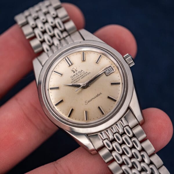 Hand-held angled view of Omega Seamaster 168.024 with pointed hands, applied markers and crown at three