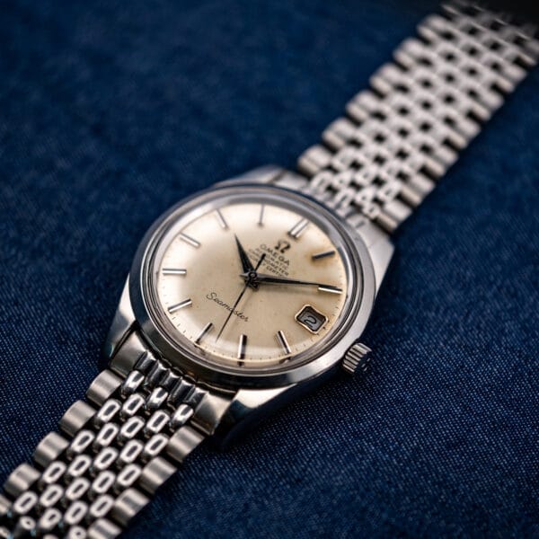 Omega Seamaster 168.024 resting at an angle on blue cloth with its beads-of-rice bracelet stretched out