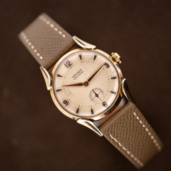 Front view of Gruen Precision 415/932 showing the patinated off-white dial, cross-lined seconds and curved strap