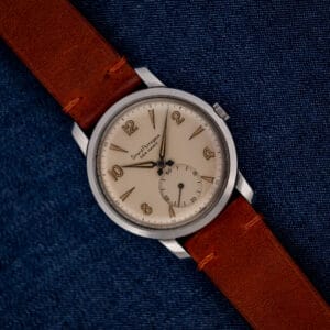 Girard Perregaux Sea Hawk with eggshell dial and brown leather strap resting diagonally on blue fabric