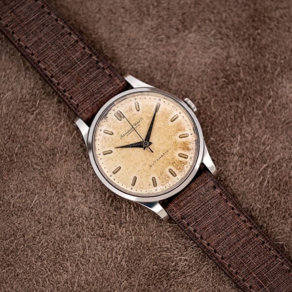 Complete IWC automatic laid diagonally with brown textured strap and stainless steel case