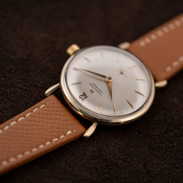 Low oblique view of Hamilton Masterpiece showing the silver dial, slender markers and stitched leather strap
