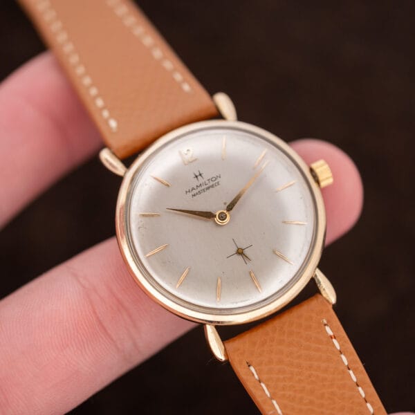 Close angled Hamilton Masterpiece held between fingers, with pointed hands and cross-lined subsidiary seconds visible