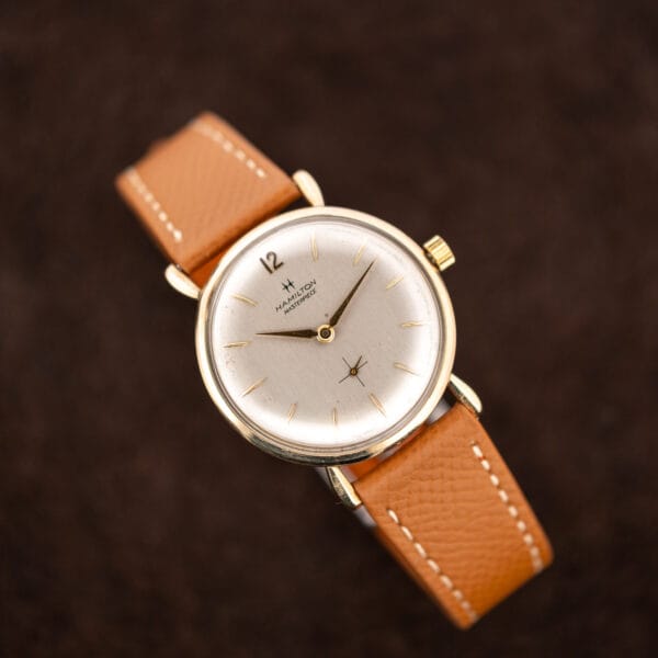 Front view of Hamilton Masterpiece on an arched leather strap, with twelve angled toward the upper left