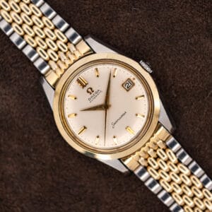 Omega Seamaster 14744-1 resting diagonally on brown fabric with white dial and two-tone bracelet