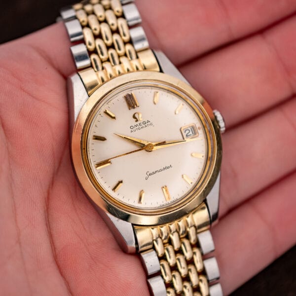 Omega Seamaster 14744-1 resting in an open hand, displaying the white dial and two-tone bracelet