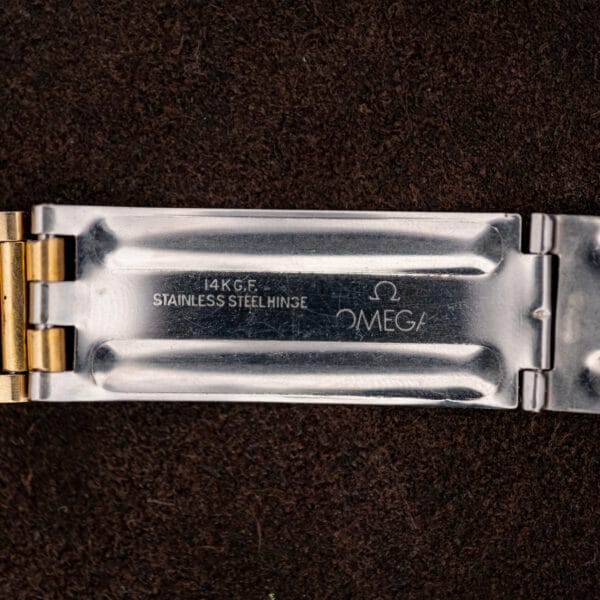 Open Omega Memomatic 166.072 bracelet clasp showing the Omega signature, gold-filled marking and stainless steel hinge lettering