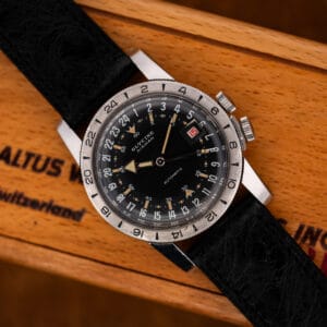 Glycine Airman on its black ostrich strap, resting diagonally across a wooden box with the dial visible