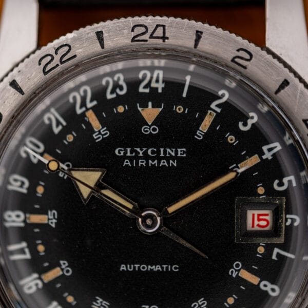 Glycine Airman dial close-up showing the broad arrow hour hand, 24-hour numerals and red date display