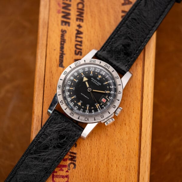 Full-length Glycine Airman with black ostrich strap laid across a wooden box bearing Glycine and Altus lettering