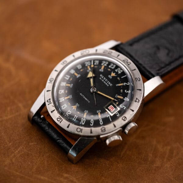 Three-quarter view of the Glycine Airman with its strap folded underneath and both crown-side controls visible