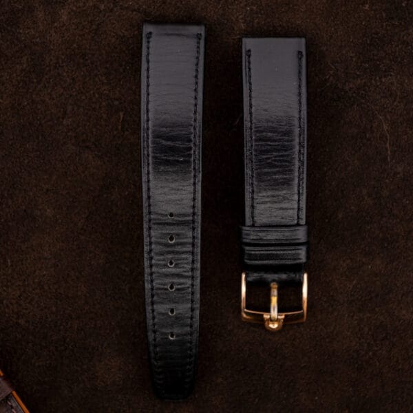 Detached black strap and gold toned buckle photographed alongside the Omega Constellation 167.005 accessories