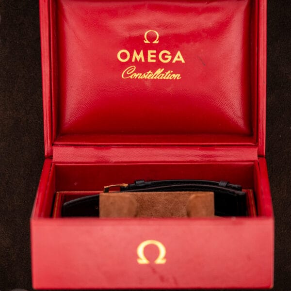 Open red Omega Constellation presentation box showing gilt interior branding and the watch cushion